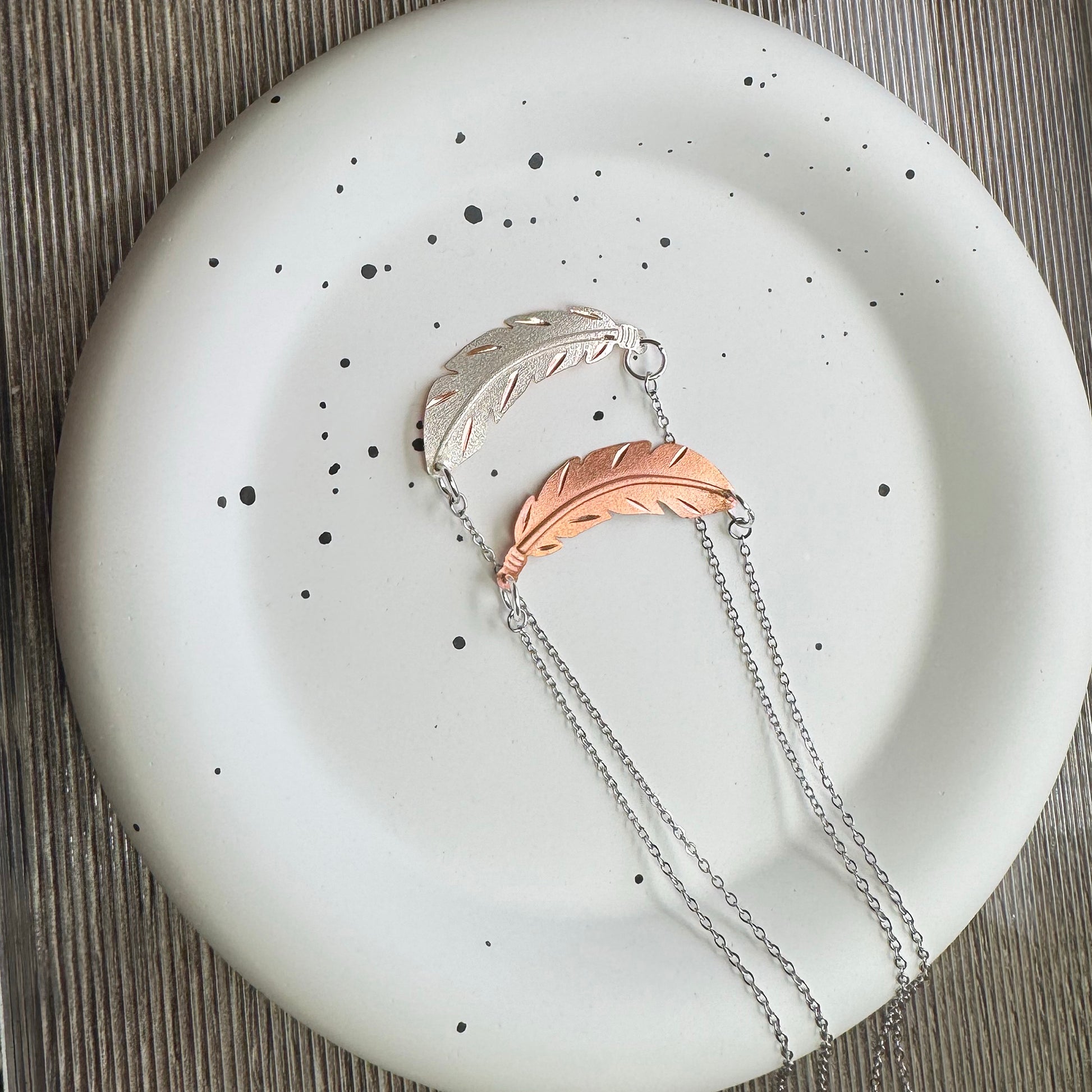 Necklace with feather pendants on a speckled plate