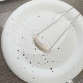 Close-up of silver color feather pendant with artistic copper background